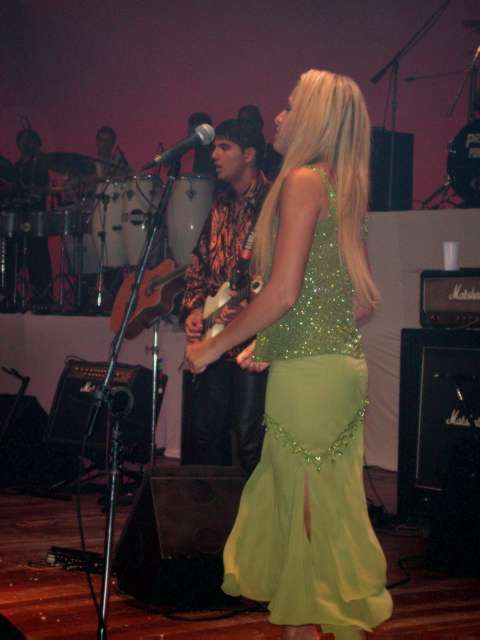 Vocalista feminina de vestido verde no palco