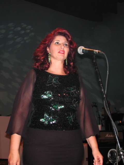 Vocalista de cabelo ruivo cantando no microfone