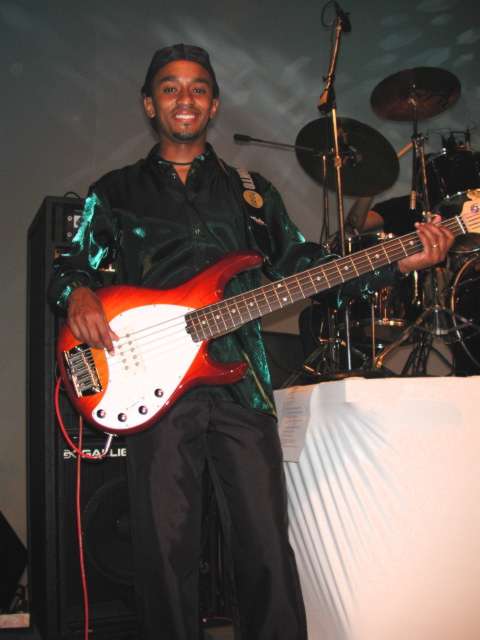 Baixista sorrindo e segurando um contrabaixo no palco