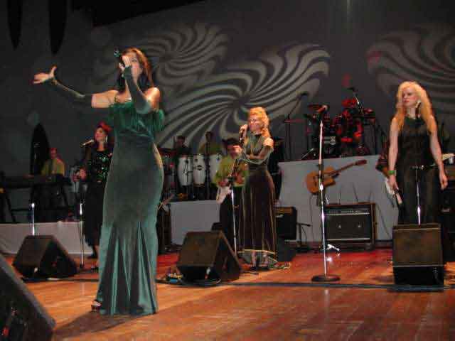 Apresentação em grupo com cantoras e músicos no palco