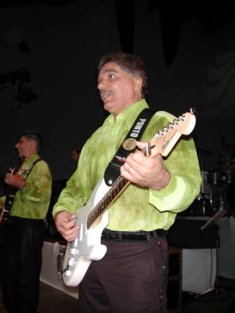 Guitarrista tocando guitarra branca no primeiro plano