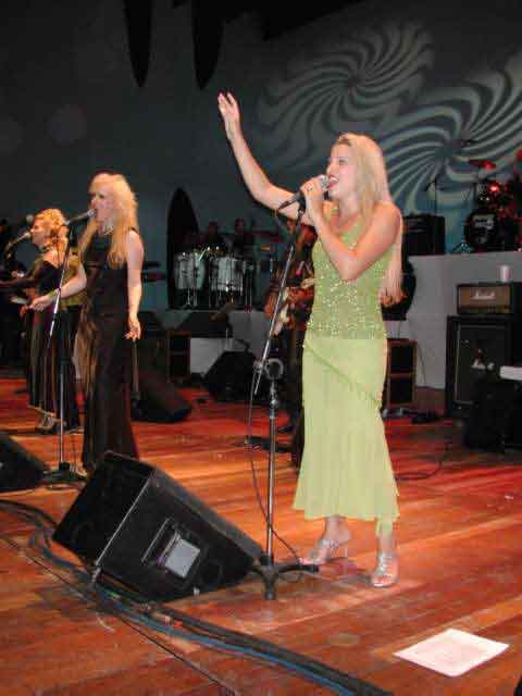 Cantora com vestido verde e braço erguido durante a música