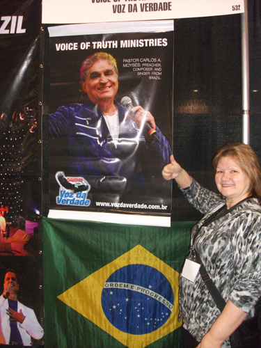 Mulher ao lado da bandeira do Brasil no estande