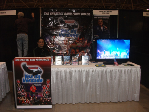 Visão frontal da mesa do estande Voz da Verdade com DVDs