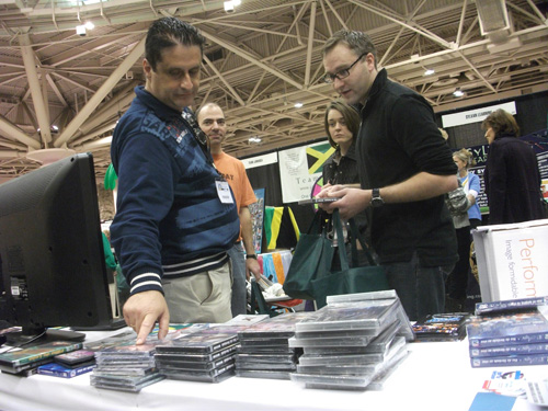 Visitante examinando mídias em CD/DVD expostas na mesa do estande